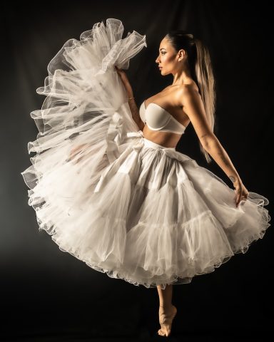 Bailarina con falda de tul blanca, posando con movimiento elegante.